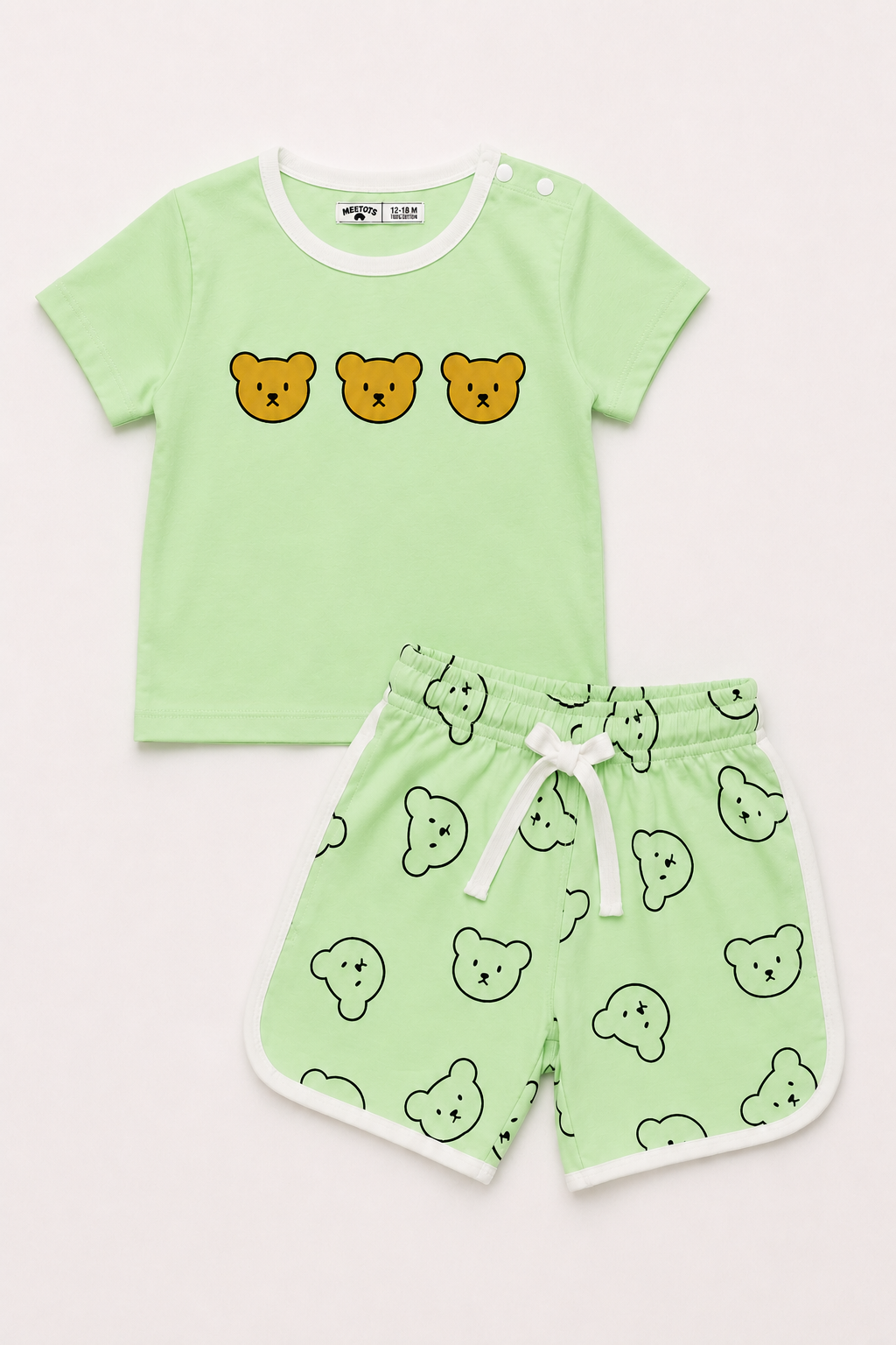 A two-piece baby clothing set featuring a light green short-sleeve t-shirt with three yellow bear faces on the chest, and matching light green shorts with a white drawstring and an all-over bear face pattern.