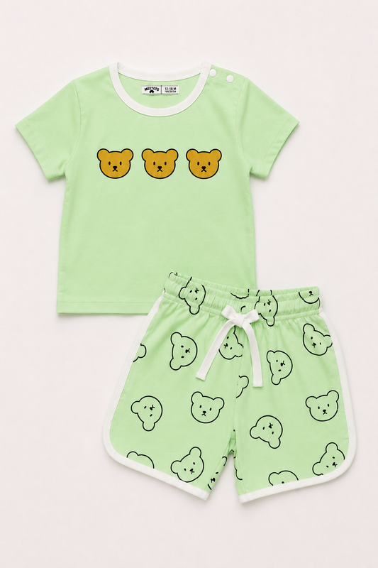 A two-piece baby clothing set featuring a light green short-sleeve t-shirt with three yellow bear faces on the chest, and matching light green shorts with a white drawstring and an all-over bear face pattern.
